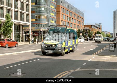 Two Greater Manchester Police Tactical Aid Unit vans travelling through Manchester on a bright sunny day. UK law enforcement. Stock Photo