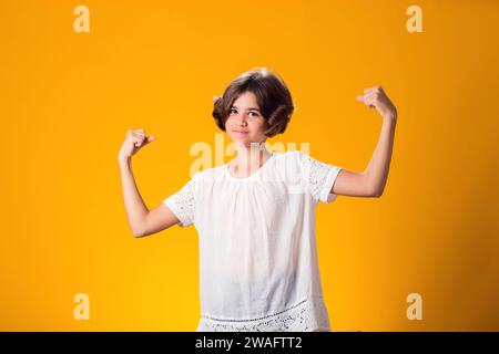 Smiling kid girl showing success over yellow background. Luck concept Stock Photo