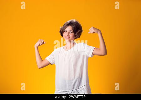 Smiling kid girl showing success over yellow background. Luck concept Stock Photo
