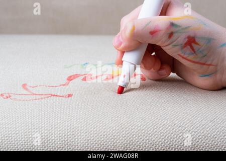 Unrecognizable child drawing felt-tip pens on the sofa or a carpet. Daily life stain concept. Stock Photo