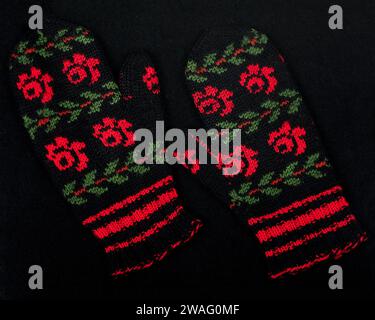 Colorful warm woolen mittens on black background. Hand-knitted, handiwork of woolen yarn. Stock Photo