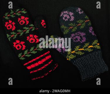 Colorful warm woolen mittens on black background. Hand-knitted, handiwork of woolen yarn. Stock Photo
