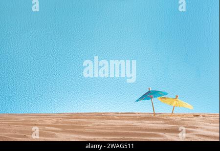 cocktail umbrellas in the sand on a blue background, abstract texture for design, copyspace, summer vacation concept Stock Photo