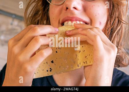 hands of a young girl take hard cheese, thinly sliced, and eat it Stock Photo