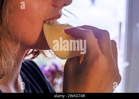 hands of a young girl take hard cheese, thinly sliced, and eat it Stock Photo