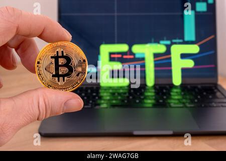 Cryptocurrency coins next to a cell phone showing candlestick chart and ETF message Stock Photo