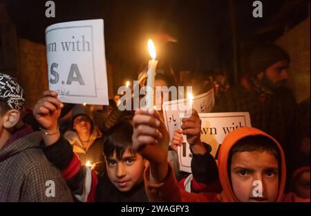 Srinagar, India, 04/01/2024, Kashmiri Shia Muslims hold 'Shame on Israel'' placards and candles during a candlelight vigil. In the outskirts of Srinagar, Kashmir, Shia Muslims from the Kashmiri community held a candlelight vigil expressing their opposition to Israel and the United States. The solemn gathering took a tragic turn as 84 individuals lost their lives, and numerous others sustained injuries in a blast during a ceremony commemorating the death of Iranian General Qassem Soleimani. The Islamic State claimed responsibility for the two destructive explosions that resulted in the deaths o Stock Photo