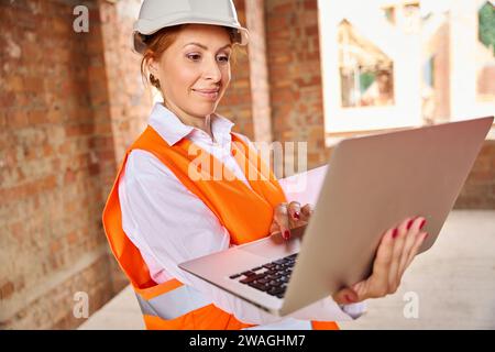 Construction specialist working on portable computer inside uncompleted building Stock Photo