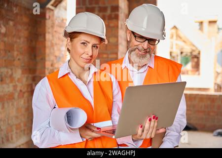 Construction professionals using portable computer in unfinished dwelling house Stock Photo