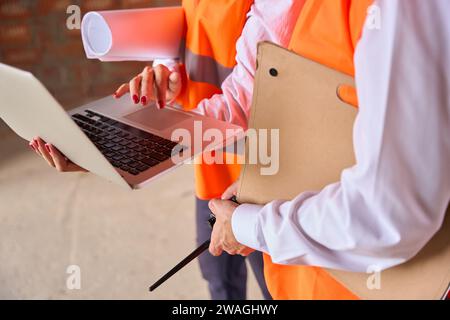 Construction commission checking data on laptop during building site inspection Stock Photo