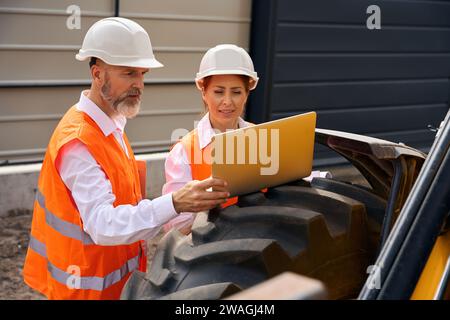 Team of construction specialists using together computer during site inspection Stock Photo