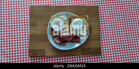 Breakfast on a plate. Poached eggs, toast and bacon, on a plate, using a cutting board as a tray. Stock Photo