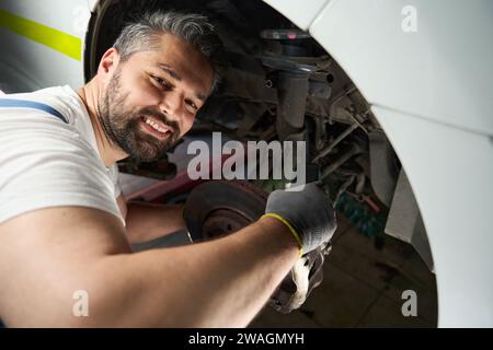 Cheerful vehicle mechanic checking client car with digital device Stock Photo