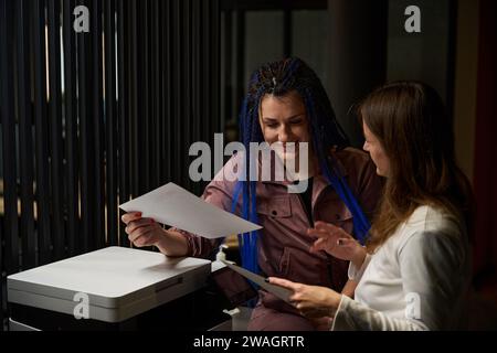Female colleagues making copies of private documents of office employees Stock Photo
