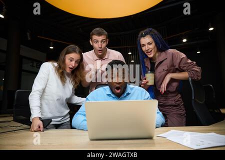 Shocked multiracial team of managers looking at laptop screen Stock Photo