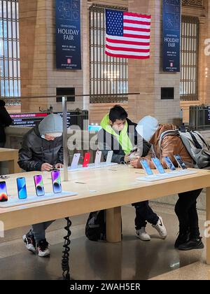 Young men checking out the newest Apple iphones at the Apple Store at Grand Central Stration in Manhatrtan, New York City. Stock Photo