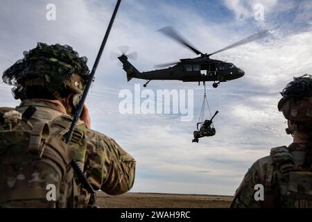 Artillery Soldiers from Bravo Battery, 3rd Battalion, 320th Field Artillery Regiment, 3rd Brigade Combat Team, 101st Airborne Division conduct sling-load operations and elevator drills with 3rd Attack Helicopter Battalion, 1st Aviation Regiment, 1st Combat Aviation Brigade, 1st Infantry Division on Mihail Kogalniceanu Air Base, Romania, Jan. 4, 2024, to increase readiness and proficiency in air assault operations. (U.S. Army photo by Pfc. Aiden O'Marra) Stock Photo