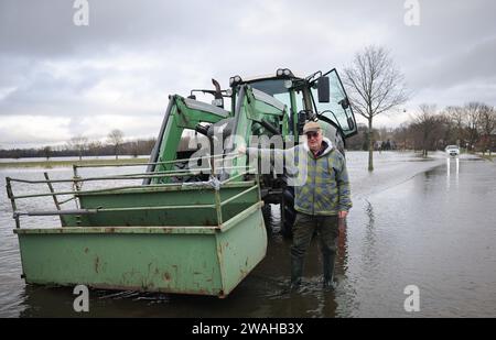 Hagen Grinden, Germany. 04th Jan, 2024. Harm Beckröge, a farmer in Etelsen, stands next to his tractor on the flooded road between Etelsen and Hagen-Grinden. The village of Hagen-Grinden near Bremen was cut off from the outside world for days by the flood. Credit: Christian Charisius/dpa/Ģ����ý Live News Stock Photo