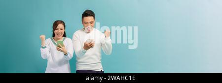 Excited people man and woman looking at each other while both using mobile phones over blue Stock Photo
