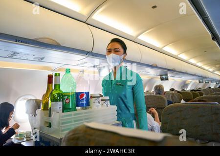 HO CHI MINH CITY, VIETNAM - MARCH 24, 2023: Vietnam Airlines flight attendant in uniform serve drinks to passengers on board of Airbus A321. Stock Photo