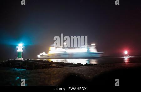 On its journey to Rostock harbour, a ferry passes a lighthouse, Warnemuende, 09.02.2023 Stock Photo