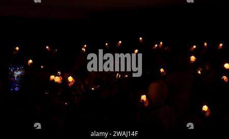 holding a burning candle against a dark background Stock Photo