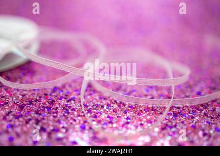 Defocused random white fabric ribbon on bright pink glitter texture background with shimmering bokeh and vibrant color Stock Photo