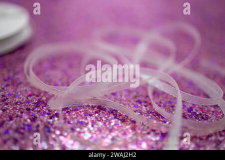 Defocused random white fabric ribbon on bright pink glitter texture background with shimmering bokeh and vibrant color Stock Photo