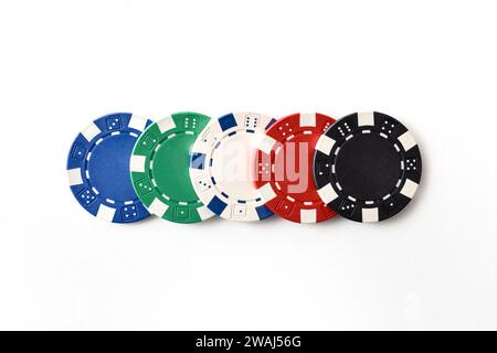 Casino background with detail of five different colored plastic chips in a row on white isolated background. Top view. Stock Photo