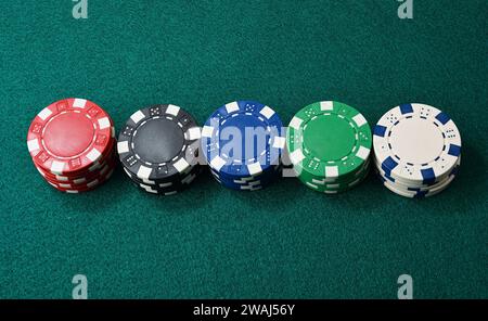 Pile of multi-colored gambling chips lined up on green gaming mat. Top view. Stock Photo