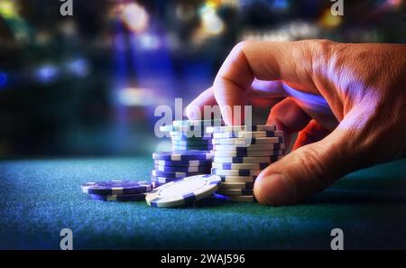 Hand betting game chips on felt mat with game room in the background. Front view. Stock Photo