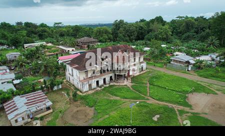 An isolated traditional wooden house stands in a rural landscape, surrounded by vibrant green grass and lush trees Stock Photo