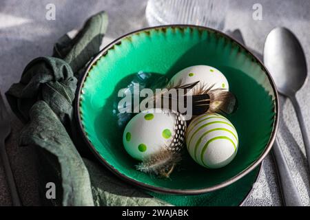 High angle closeup of Easter table setting, showcasing a vibrant green ceramic plate with two decorative Easter eggs adorned with white and green patt Stock Photo