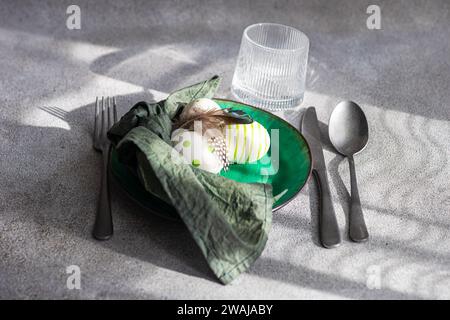 High angle of Easter table setting, showcasing a vibrant green ceramic plate with two decorative Easter eggs adorned with white and green patterns and Stock Photo