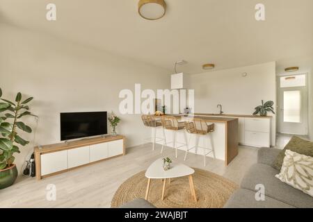 Coffee table with sofa and television in spacious living room with chairs by island in kitchen at contemporary house Stock Photo