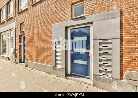 Blue front door and mailboxes of brick apartment building in city during sunny day Stock Photo