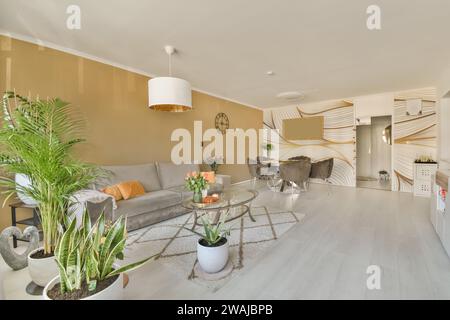 Comfortable couch with coffee table and various houseplants arranged in modern spacious living room with dining zone in background Stock Photo