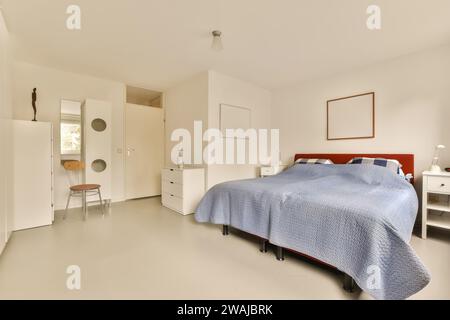 Interior of spacious bedroom with large comfortable blue bed and dresser in contemporary light apartment Stock Photo