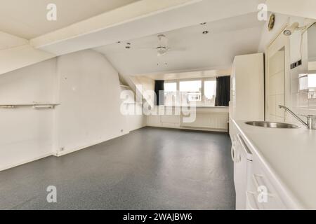 Sink with faucet and white cabinets in empty spacious kitchen with ceiling fan in modern apartment Stock Photo