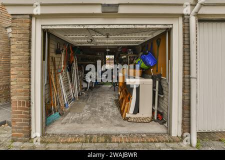 Gardening equipment and furniture with other objects stored in open garage of modern house Stock Photo