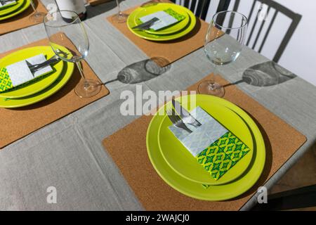 Vibrant green-themed table setting with origami-folded napkins in a cozy living room ambiance. Stock Photo