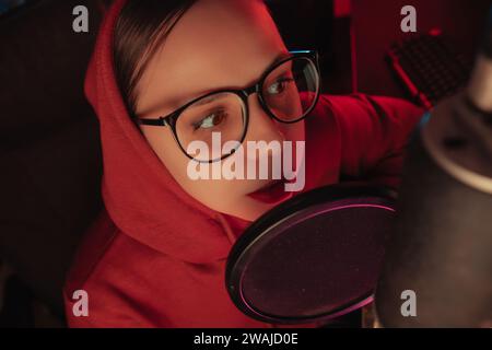 A woman sits in front of a microphone, and ready to record. Stock Photo