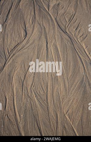 Wet beach sand etched by gentle waves, resembling nature's canvas of shallow ridges in the sand Stock Photo