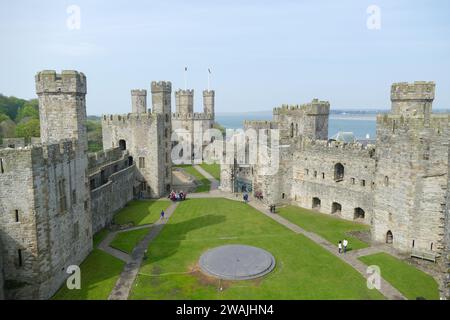 Caernarfon, Wales, United Kingdom - May 1 2017: Historic Caernarfon Castle, medieval fortress aerial drone view, popular tourist landmark, Wales, Unit Stock Photo