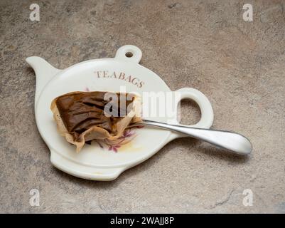 used english breakfast teabag and silver spoon on a tea pot shaped plate Stock Photo