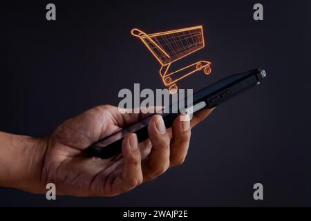 Hand holding smartphone with shopping trolley icon. Online shopping, business concept. Stock Photo