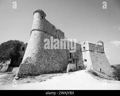 A majestic medieval castle stands atop a grassy hill, surrounded by a cloud-filled sky Stock Photo