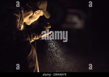 A Man with a Flashlight in His Hand During Night Time Hours Looking For Something. Stock Photo