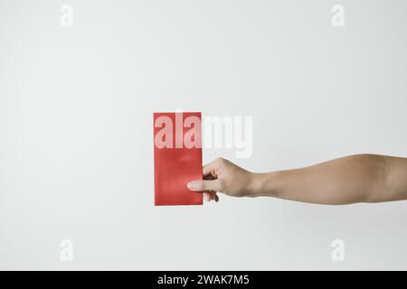 A hand holds angpao or red monetary gift on white background. Chinese New Year concept. Gong Xi Fa Cai. Stock Photo