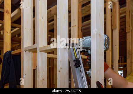 Builder uses an air hammer to nail wooden beams framework for ...